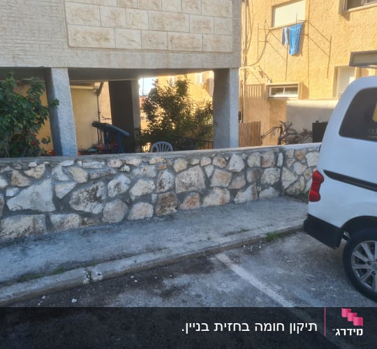 קיר אבן טבעית בחצר לצד רכב עבודה ממותג
